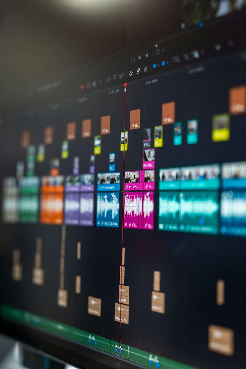 Computermonitor zeigt eine Videobearbeitungssoftware-Timeline mit Clips und Wellenformen.
